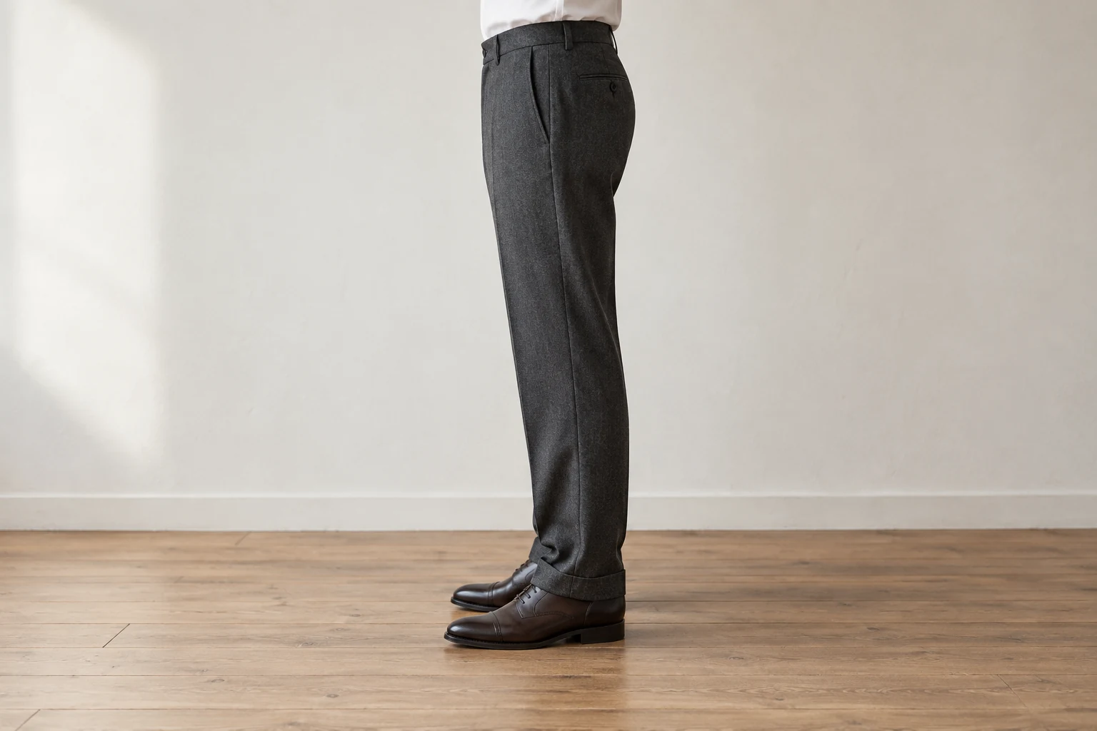 A side view shows charcoal wool trousers falling with a slight break over dark brown oxford shoes