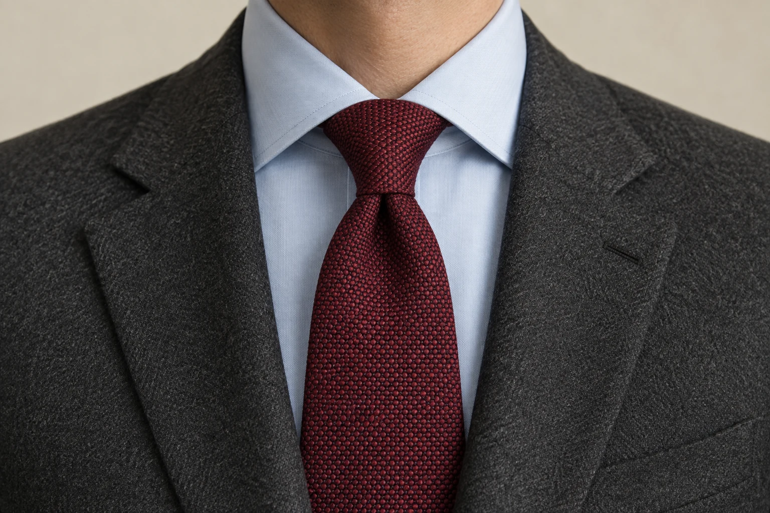 A burgundy textured half Windsor knot with a center dimple sits under a pale blue spread collar